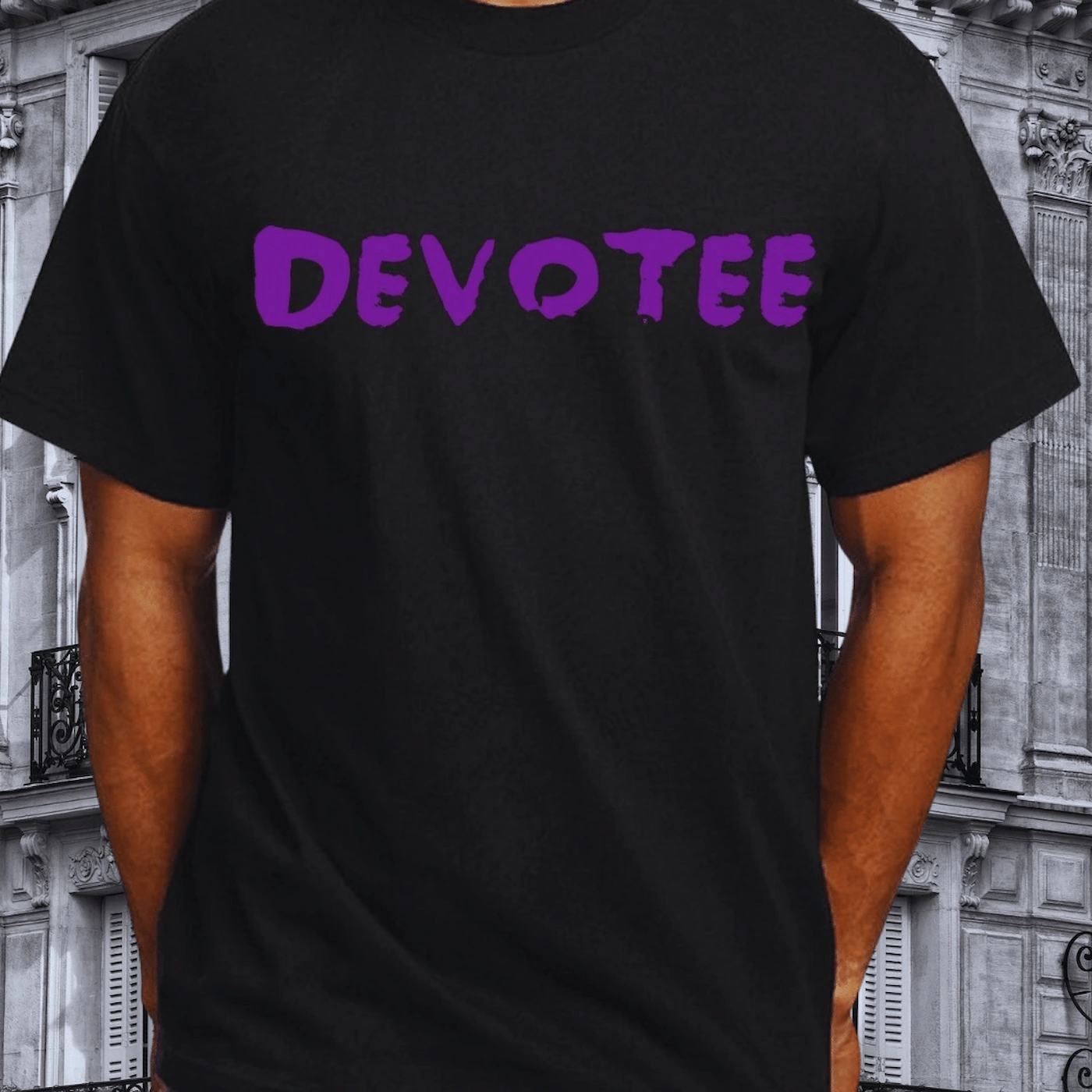 A Devotee wearing a black t-shirt with DEVOTEE printed in purple, photographed on a Parisian street with classical architecture in the background.